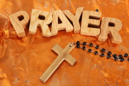 Wooden letters spelling PRAYER beside a wooden cross